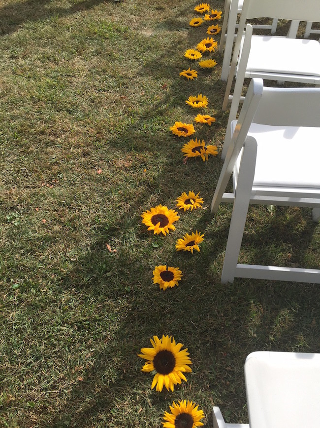 sunflowers lining the aisle of the ceremony - Flowers by Events by Amy