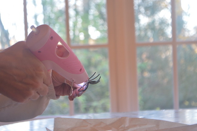 Using Glue Gun to Attach Spiders to Candles