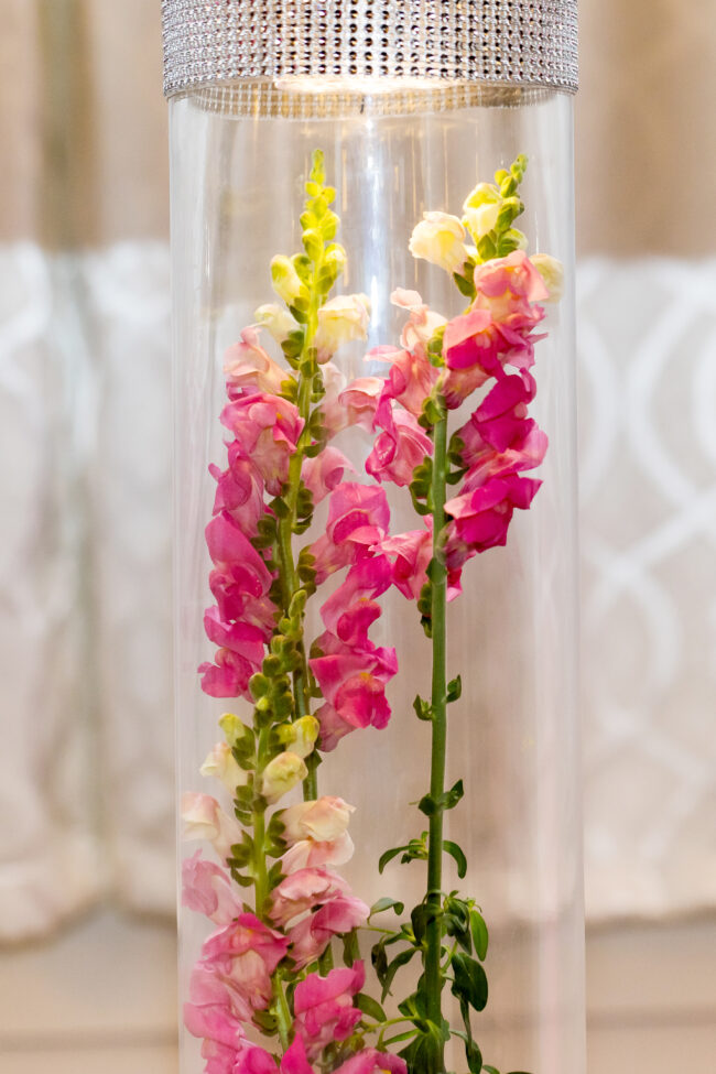 Giant vase centerpiece with florals and picture toppers.