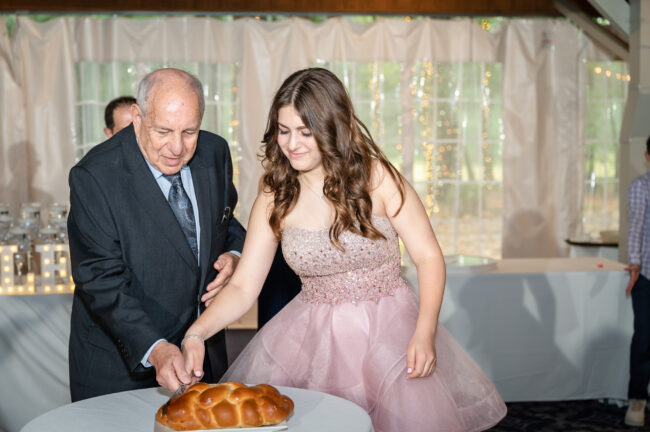Mitzvah girl and grandfather performing the Hamotzi