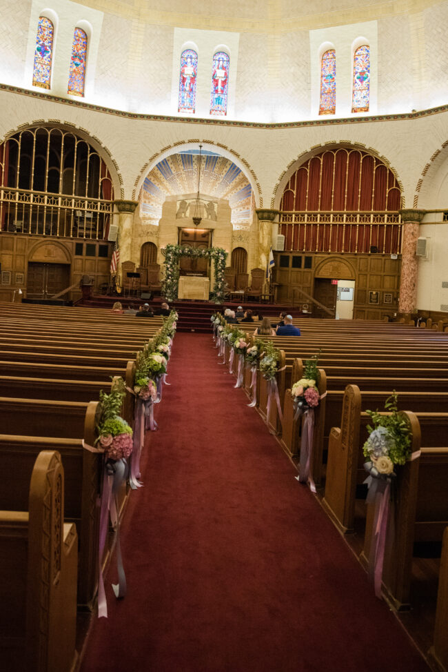 Wide shot of sanctuary with florals lining the pews