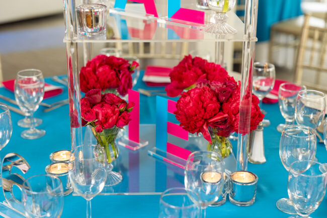 Close-up of floral centerpices on acrylic stands with silver votives