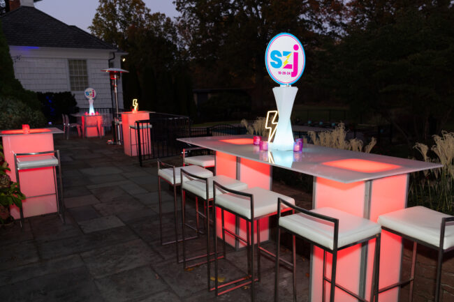 Light-up communal tables with neon centerpiece and logo'd topper