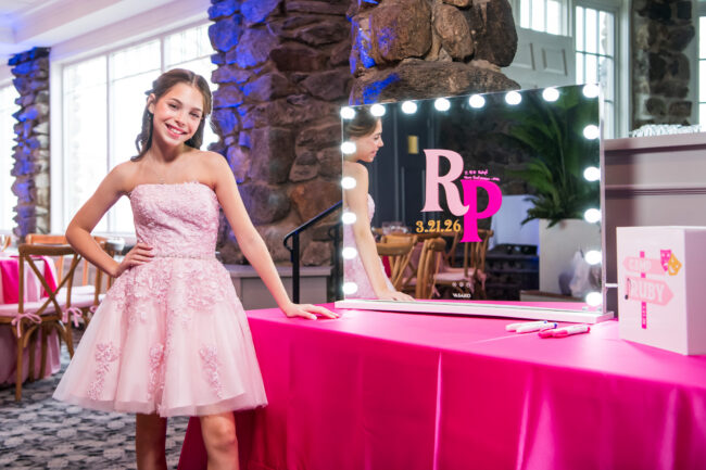 Mitzvah girl poses in front of sign-in mirror